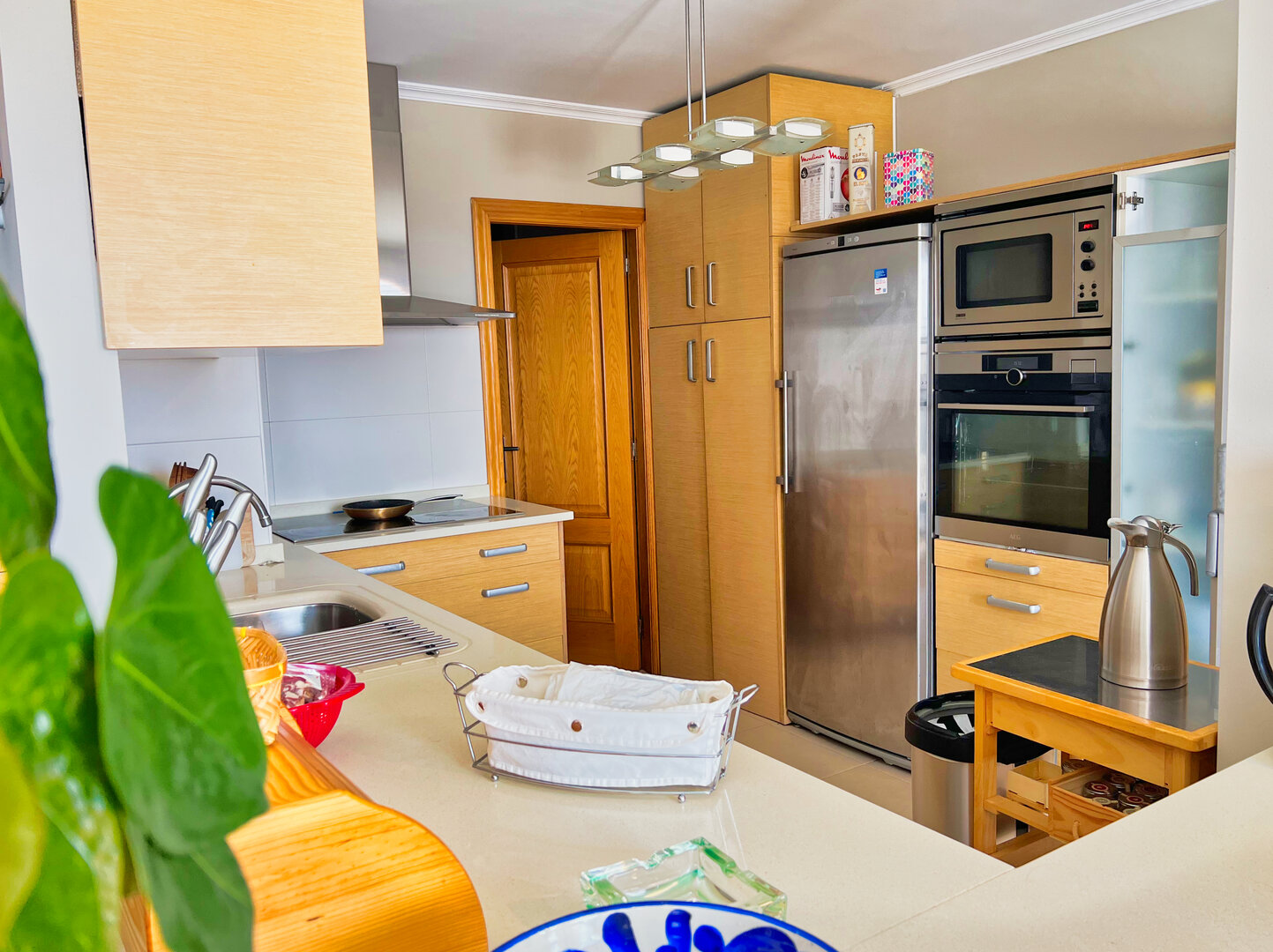 Cocina completamente equipada con electrodomésticos premium: nevera americana, horno, microondas integrado, encimera amplia y muebles de madera