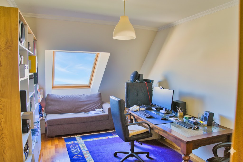 Despacho profesional con claraboya, sofá-cama, escritorio amplio y luz natural ideal para trabajar o descansar