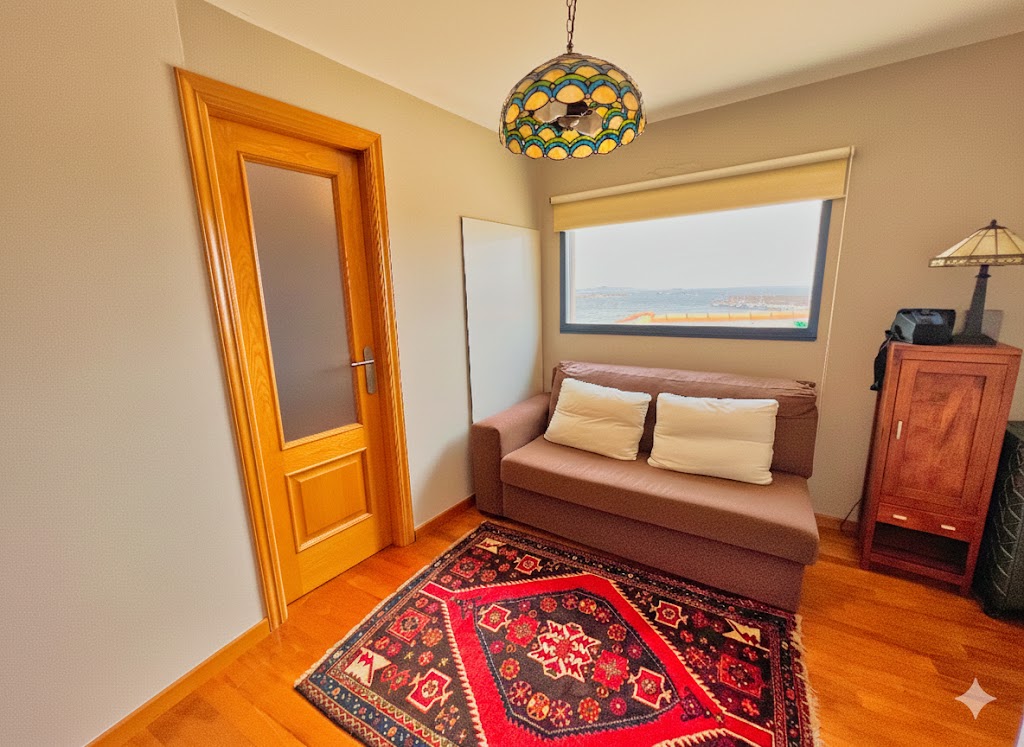 Hall del dormitorio principal con sofá-cama, lámpara Tiffany y vistas panorámicas al mar y la terraza