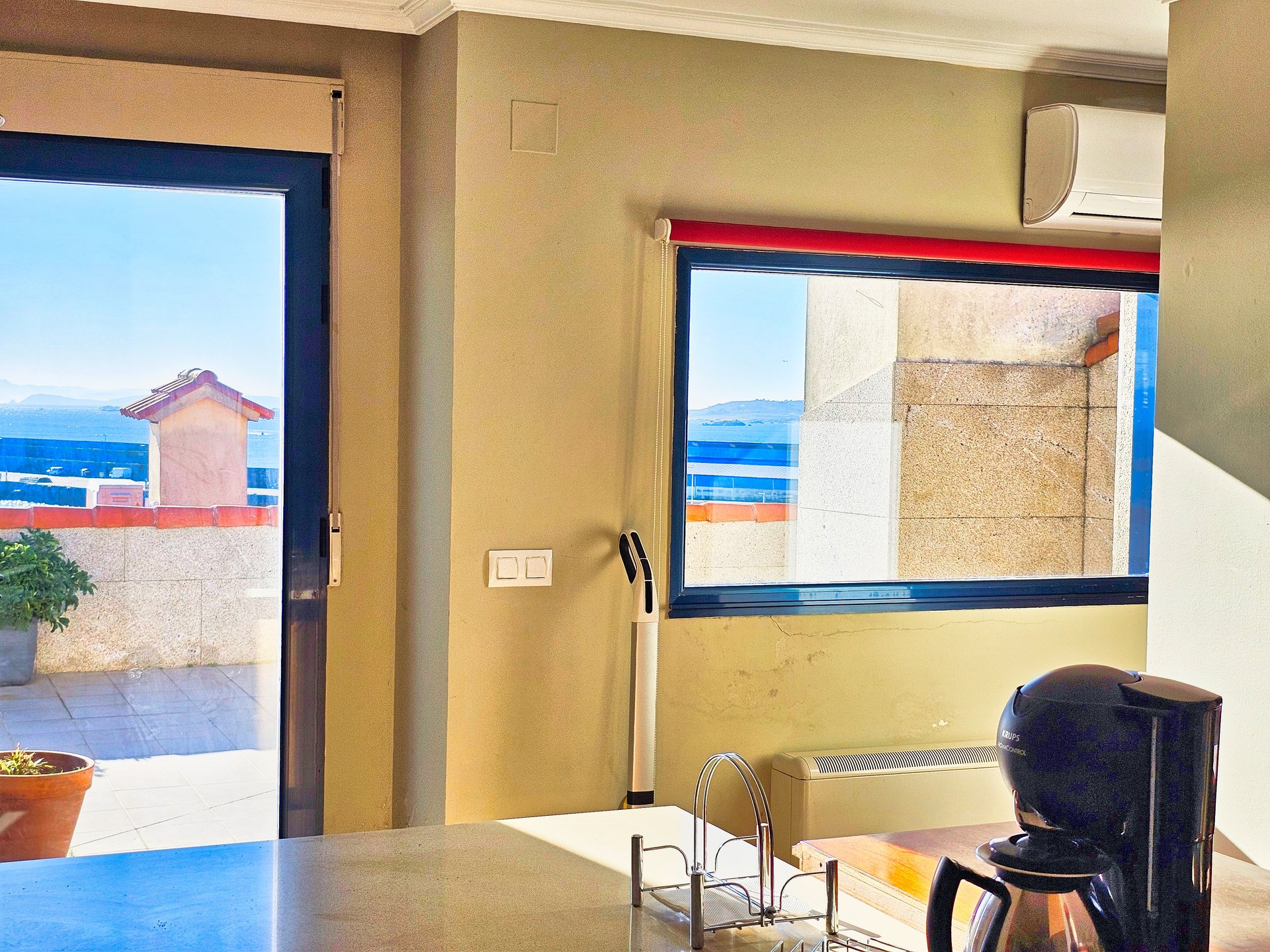 Interior del ático: cocina abierta al salón con vistas al mar y climatización