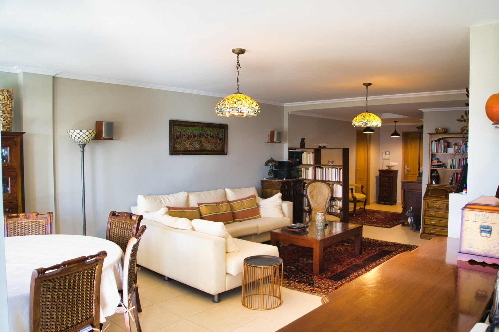 Salón principal del ático con sofá de diseño, biblioteca y alfombra oriental, vista hacia la zona de entrada