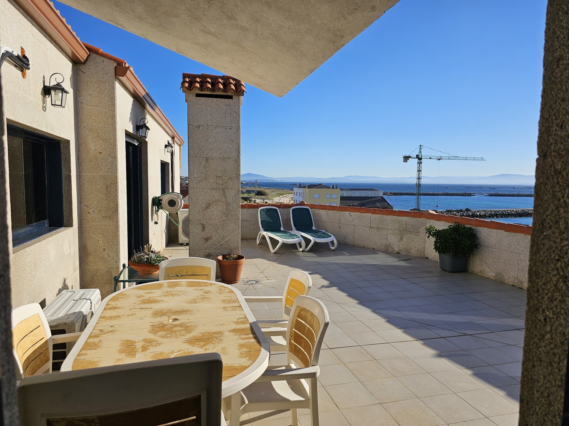 Terraza privada del ático con tumbonas y vistas panorámicas al mar