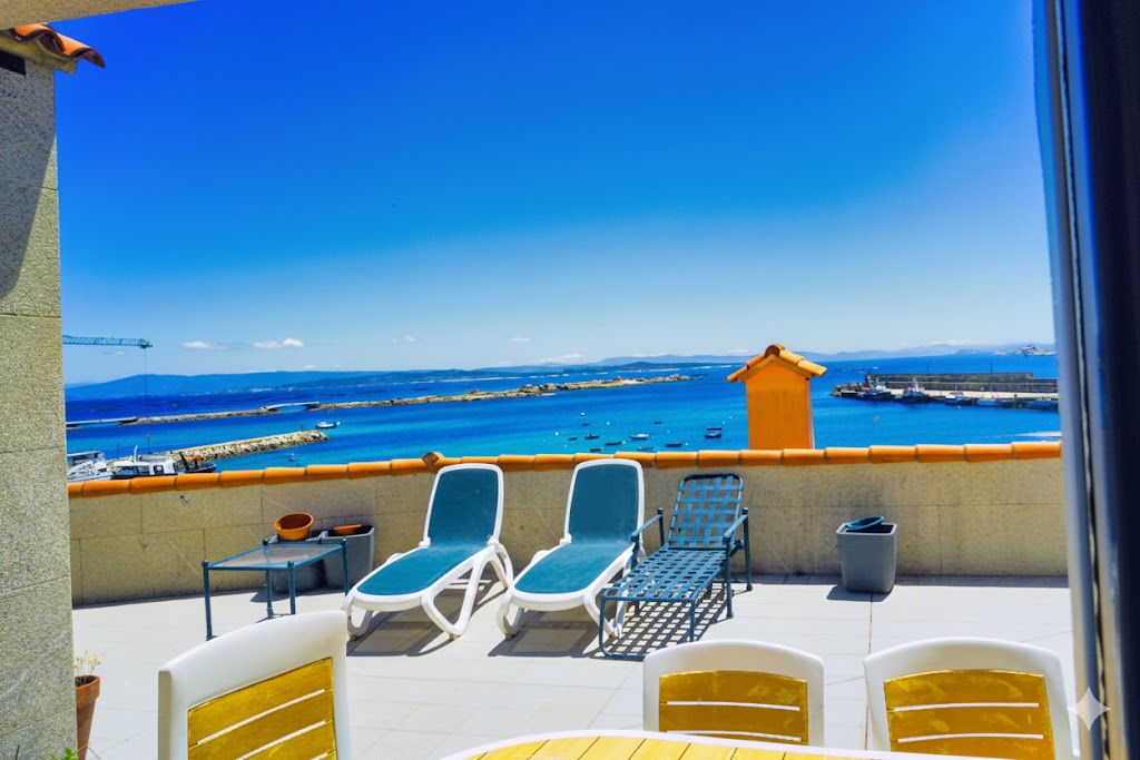 Terraza privada con tumbonas, mesa de comedor exterior y vistas espectaculares al puerto de Aguiño y las Illas Atlánticas